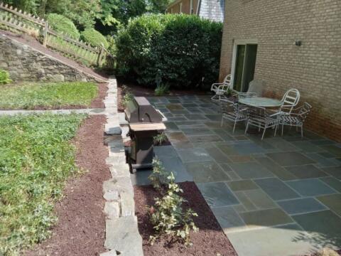 Beautiful backyard patio with stone paving, outdoor seating, and landscaped garden area.