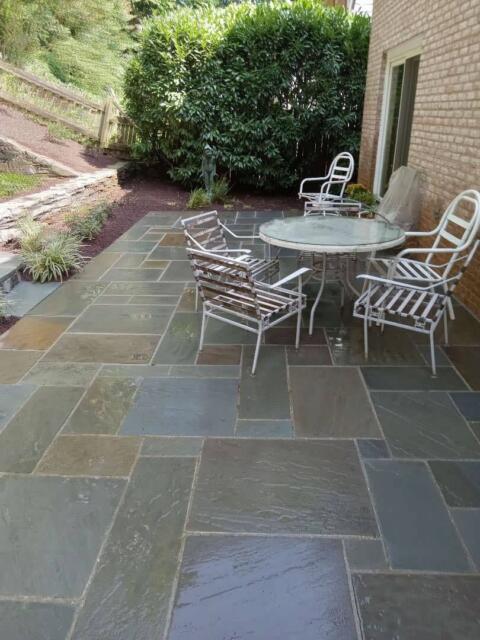 Elegant outdoor patio with stone tiles, metal chairs, and lush greenery for relaxing outdoor space.