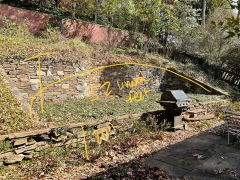 Stacked stone retaining wall with handwritten landscape plan markings.