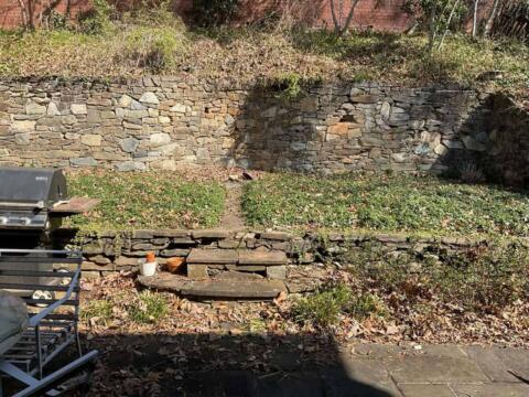 Layered stone retaining wall with landscaping and outdoor seating area.
