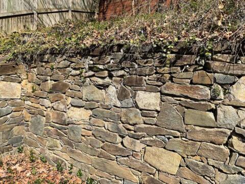 Dry stacked stone retaining wall in a backyard garden.