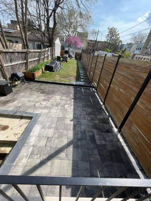 Newly installed paved patio with wooden fencing in backyard for outdoor living.