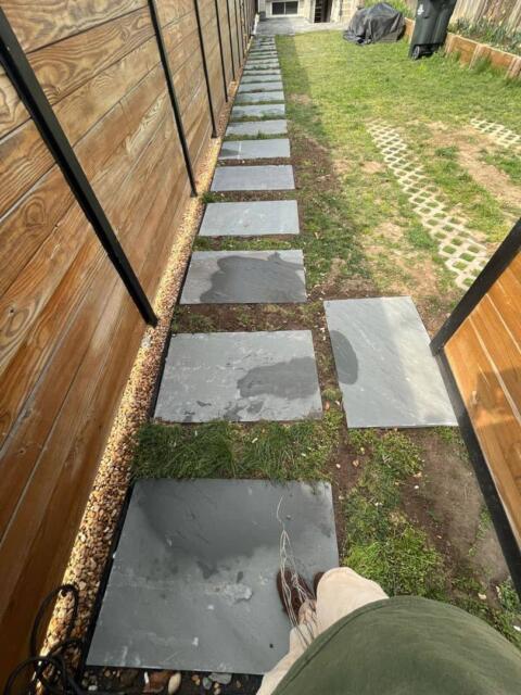 Smooth slate stepping stones in a backyard garden pathway.
