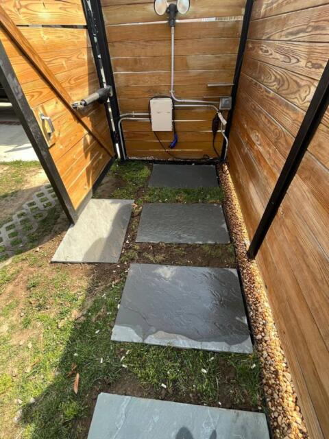 1. Outdoor shower with wooden walls and slate stepping stones.