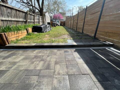 Stylish backyard with paver patio, raised garden bed, and wooden fencing for privacy.
