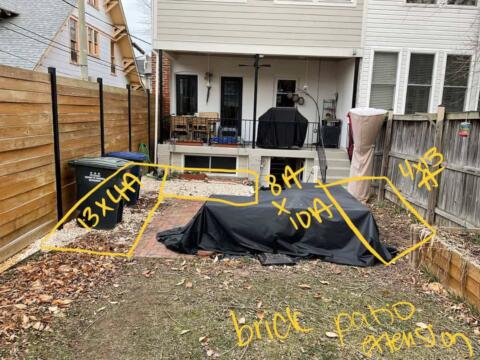 Covered patio furniture on brick paver area with yard measurements and landscaping notes handwritten in yellow.