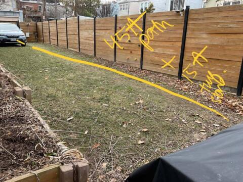 Newly installed wooden privacy fence with black posts along lawn area.