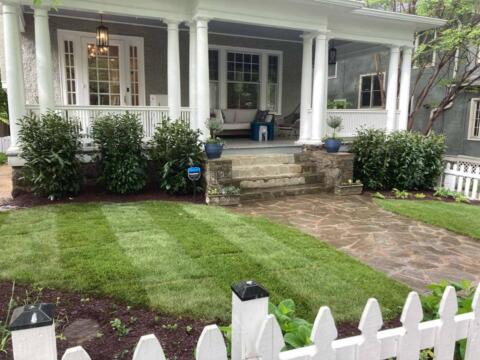 Lush front yard with manicured lawn and stone walkway leading to a cozy porch.