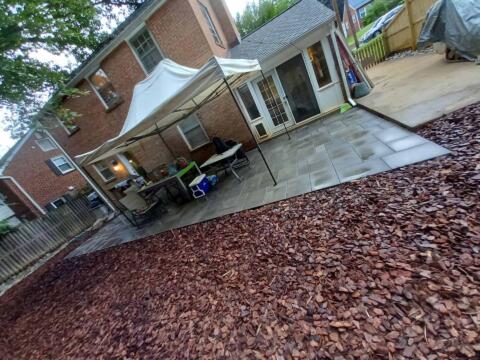 Outdoor patio with a canopy, tables, and chairs in a residential backyard.