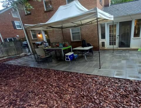 Newly installed outdoor patio with stone tiles and a white canopy at a residential backyard.